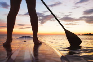 paddle board on the beach, close up of standing legs and paddle